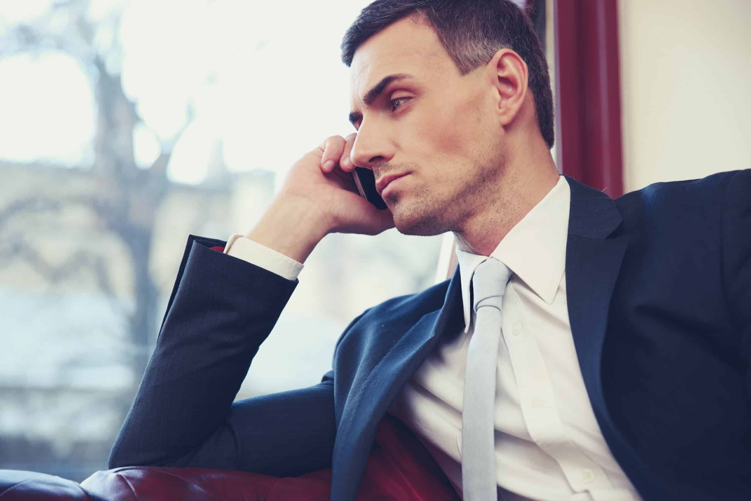 Confident businessman talking on the phone and looking in window at office